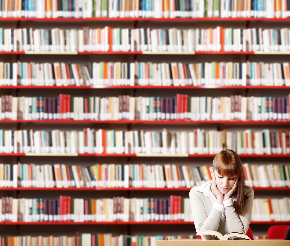 Woman seated in library with a bookcase full of books behind her